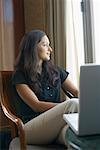 Businesswoman sitting on a chair in front of a laptop in a hotel