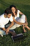 High angle view of a young couple using a laptop in a garden