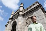 Flachwinkelansicht eines Kaufmanns steht vor einem Denkmal, das Gateway of India, Mumbai, Maharashtra, Indien