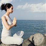 Side profile of a young woman doing yoga on a rock