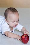 Baby boy reaching towards an apple