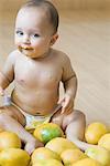 Portrait of a baby boy sitting on the hardwood floor and getting messy with mangoes