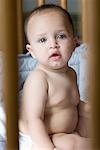 Portrait of a baby boy sitting in a crib