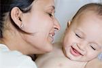 Close-up of a young woman loving her baby boy and smiling