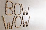 Close-up of texts BOW WOW made with dog biscuits on a white surface