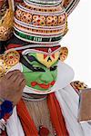 Gros plan d'un interprète de danse Kathakali appliquer le maquillage sur son visage