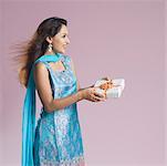 Side profile of a mid adult woman in salwar kameez and holding a gift box