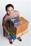 High angle view of a mid adult woman holding a stack of gift boxes