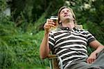 Man holding a glass of beer sitting in a lawn chair