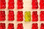 A yellow gummy bear between red gummy bears