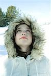 Teen girl wearing parka in snow, looking up