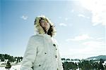 Teen girl standing in snowy landscape, low angle view