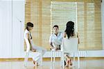 Three adults sitting in chairs, having therapy session, looking serious