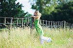 Young woman leaning against rural fence with eyes closed