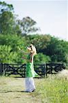 Woman blowing bubbles on rural path, side view