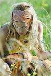 Young woman crouching to pick flowers in field, close-up