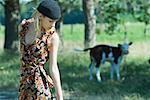 Young woman in sundress walking past cow, looking down