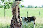 Young woman in sundress walking toward cow, side view