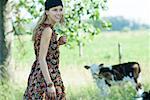 Young woman walking toward cow, smiling, looking away