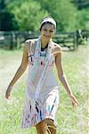 Young woman walking in rural setting, smiling at camera