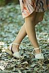 Young woman standing with legs crossed at knees, cropped view