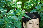 Jeune femme parmi les plantes, les yeux fermés, recadrée vue