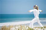 Junge Frau stehend auf Dünen, sich fit halten, Ozean im Hintergrund