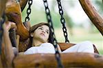 Young woman reclining on swing, looking up
