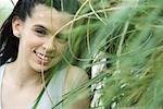 Adolescente, souriant à travers les hautes herbes à caméra