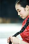 Young woman wearing traditional Chinese clothing, holding long braid