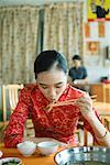 Jeune femme portant des vêtements traditionnels chinois, manger avec des baguettes