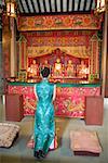 Jeune femme portant des vêtements traditionnels chinois, s'agenouillant devant le sanctuaire