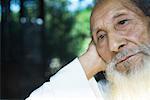 Elderly man leaning head against hand, looking away, close-up