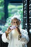 Elderly man wearing traditional Chinese clothing using camera phone