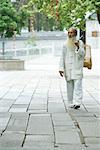 Elderly man wearing traditional Chinese clothing carrying bird cage over shoulder