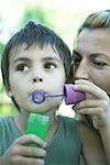 Boy and mother blowing bubbles, close-up