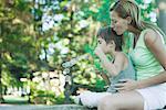 Boy and mother blowing bubbles, side view