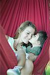 Boy and mother in hammock, boy kissing woman's face