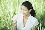 Woman in field, looking at blade of grass