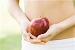 Femme tenant la pomme devant l'abdomen nu, gros plan de la partie médiane