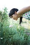 Young woman bending over to smell flowers in garden