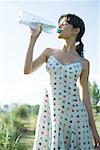 Jeune femme à boire d'une bouteille d'eau, les yeux fermés
