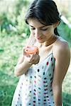 Young woman holding up tomato half, smiling