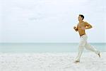 Man running on beach, full length, side view