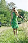 Junge Frau im Sommerkleid stehen im Feld, Rückansicht