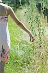 Young woman in sundress walking through field