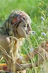 Young woman sitting in field, smelling wild flowers