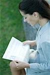 Businesswoman sitting on bench, reading newspaper