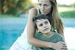 Mother and son looking opposite directions, pool in background