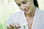 Woman plucking petal from daisy, close-up